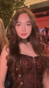 a woman with long brown hair is wearing a corset and a choker .