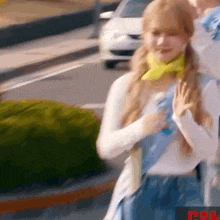 a woman in a white shirt and blue skirt is walking down the street .