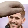 a man with a beard is smiling and a hand is reaching for his head .
