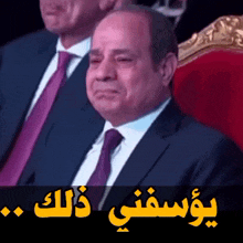 a man in a suit and tie sits in a chair