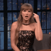 a woman in a black strapless dress is pointing her finger at her head