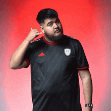 a man wearing a black adidas shirt is making a phone call