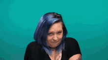 a woman with blue hair is blowing a bubble