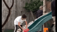 a boy is playing on a slide in a backyard