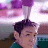 a man with purple hair has a purple bag on his head