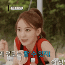 a girl in a red tank top is holding a small fan in her hand