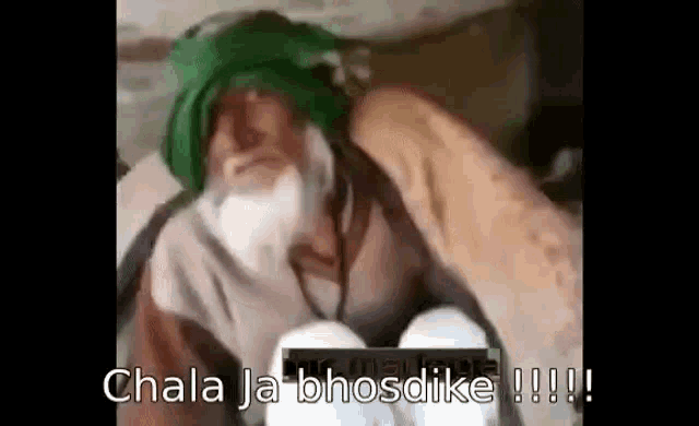 a man with a beard and a green turban is sitting on a bed with his legs crossed .
