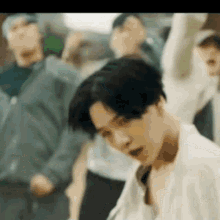 a man in a white shirt is standing in front of a crowd of people dancing .
