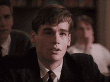 a young man in a suit and tie looks to his left