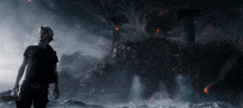 a man in a black shirt is standing in front of a giant monster