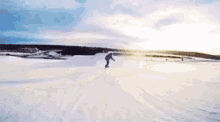 a person is riding a snowmobile down a snow covered hill at sunset .
