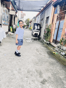 a little boy stands in a narrow alleyway with a white scooter parked in the background
