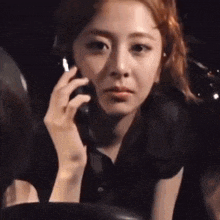 a woman is talking on a cell phone in a dark room while sitting in a chair .
