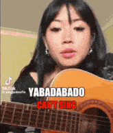 a woman playing a guitar with the words yabadabado cant sing on the bottom