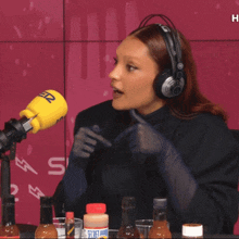 a woman wearing headphones sits in front of a yellow microphone that says secret sauce