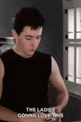 a man in a black tank top says the ladies gonna love this while looking at his phone .