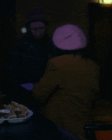 a woman in a purple hat sits at a table
