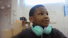 a young boy wearing headphones stands in front of a wall that says reply of the day