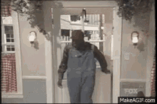 a man wearing overalls and a mask is walking through a doorway .