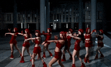 a group of women in red outfits are dancing on the sidewalk