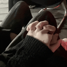 a person holding another person 's hand with a black sweater on
