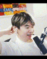 a man wearing ear buds is sitting in front of a microphone and smiling .