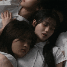 a couple of girls laying on top of each other with one of them sleeping