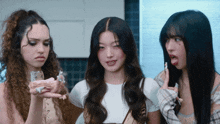 three girls are standing next to each other with one holding a bottle