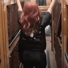 a woman with red hair is standing with her arms outstretched in a kitchen .