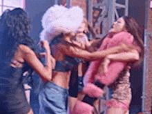 a group of women are standing next to each other on a stage and fighting .