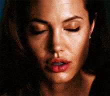 a close up of a woman 's face with her eyes closed and a tear coming out of her eye