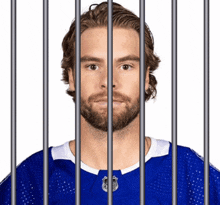 a man with a beard is behind bars wearing a blue jersey