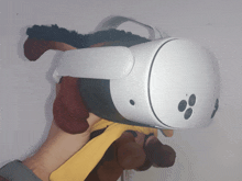 a person is holding a stuffed animal with a virtual reality headset on top of it