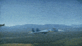 a fighter jet is flying over a field with a mountain in the background