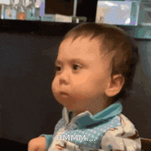 a baby is making a funny face and says hmm...