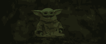 a baby yoda toy is sitting on a rock in a dark cave