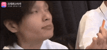 a man in a white shirt is eating a carrot with chinese writing on the bottom