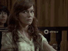 a woman sitting in front of a sign that says eltrece on it