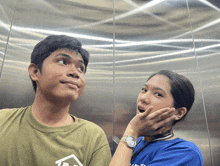 a man and a woman are in an elevator and the woman is wearing a watch that says ' rolex '