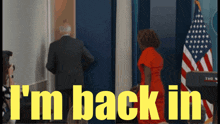 a woman in a red dress stands in front of an american flag with the words " i 'm back in " behind her