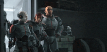 a group of men in armor are standing next to each other in a dark room .