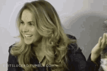 a woman with long blonde hair is smiling while holding a glass .