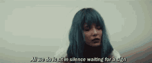 a woman with blue hair is sitting in a raincoat in silence waiting for a sign .