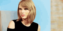 taylor swift is making a funny face while wearing a black dress .