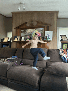 a little boy is jumping on a couch in front of a family wall