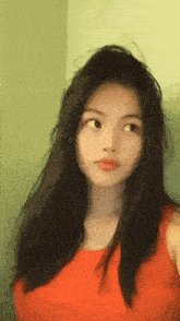 a girl with long hair is wearing a red shirt and looking at the camera