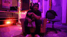 a man is sitting in a chair with purple lights around him