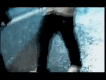 a man in black jeans is standing next to a wall in the water .
