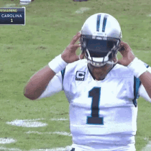 carolina panthers quarterback cam newton adjusts his helmet on the field .