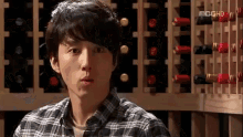 a man in a plaid shirt is standing in front of a rack of wine